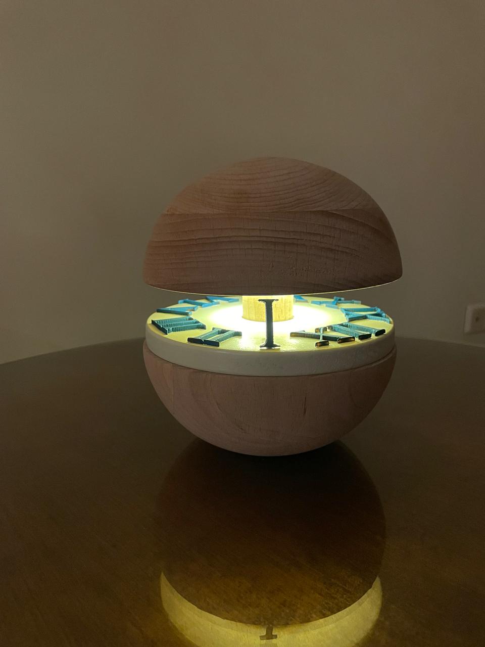 Orbit wooden prototype open, glowing dial with Roman numerals lifting from a turned beech sphere